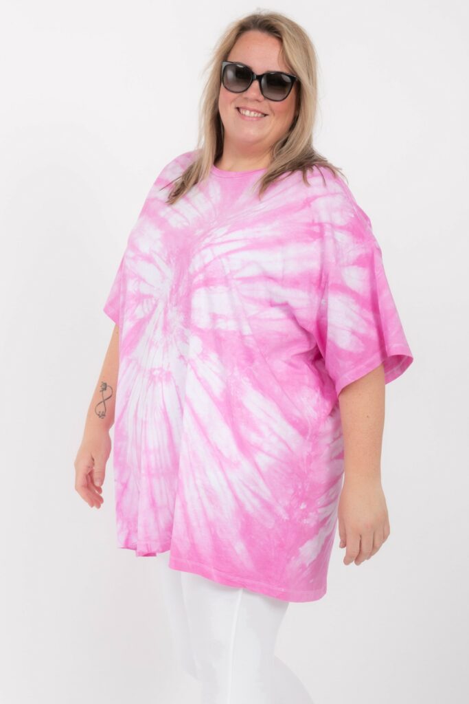 korpulente junge blonde frau im oversized pinkfarbenem batik gefärbtem T- shirt