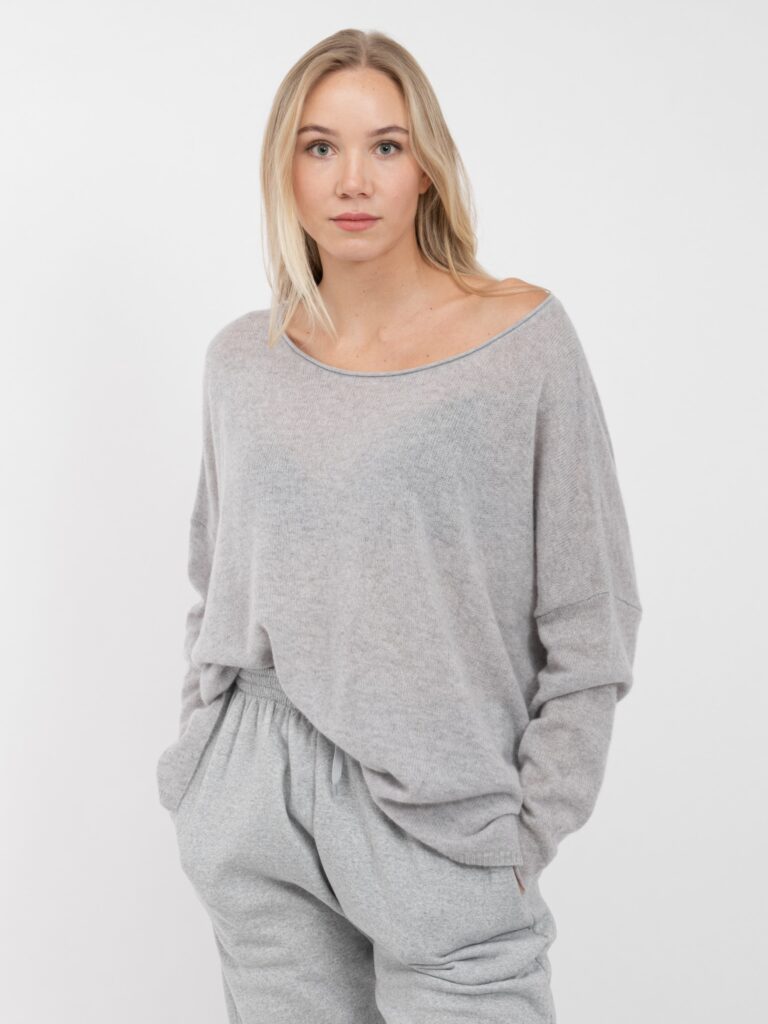 grauer oversized leicht gestrickter cashmere pullover mit großem ausschnitt an junger blonder frau